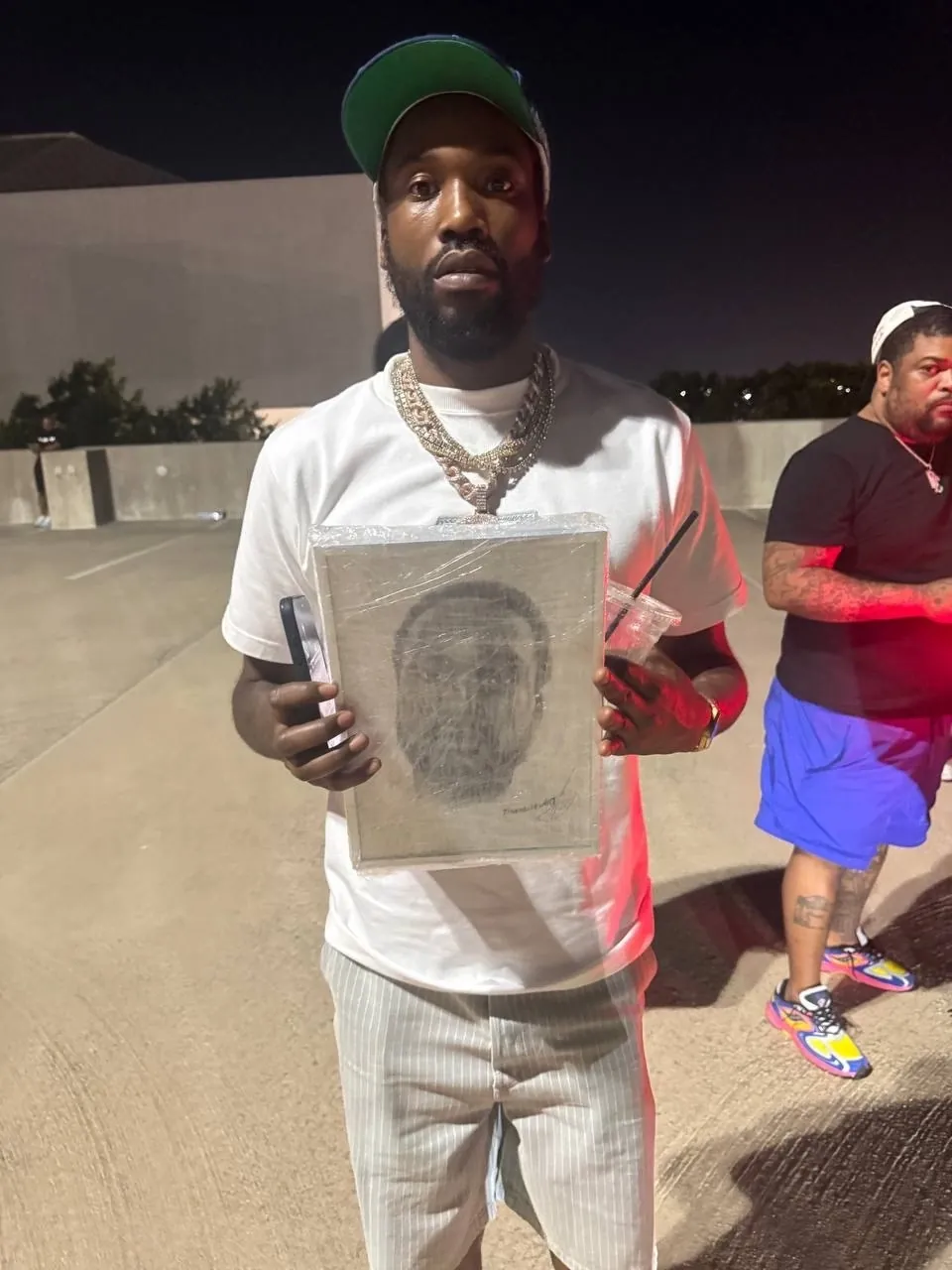 Kanye West держит портрет в защитной плёнке